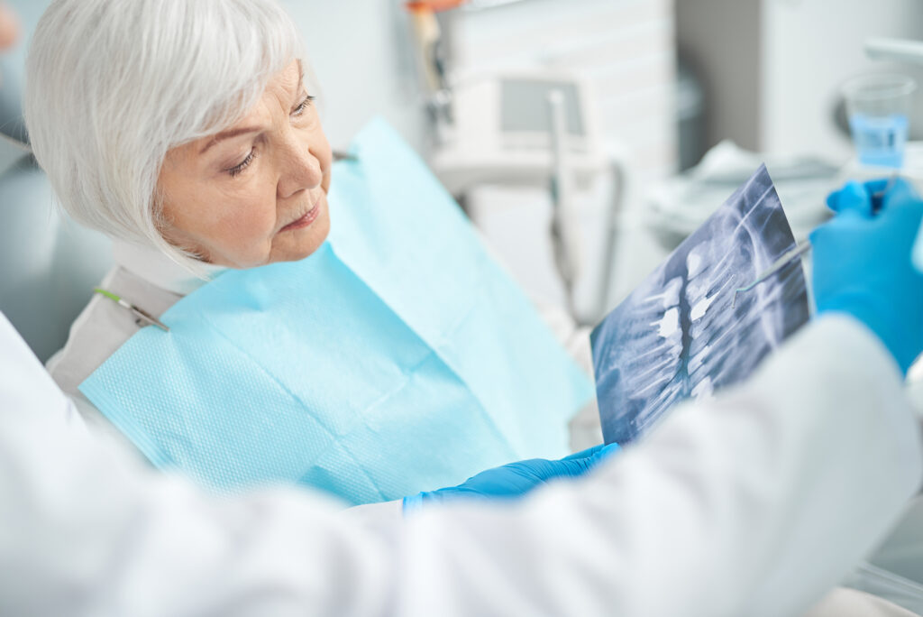 Older woman reviewing an X-ray with her oral surgeon before treatment