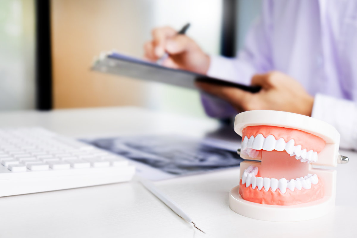 Dentist holding a tooth implant model in a dental office